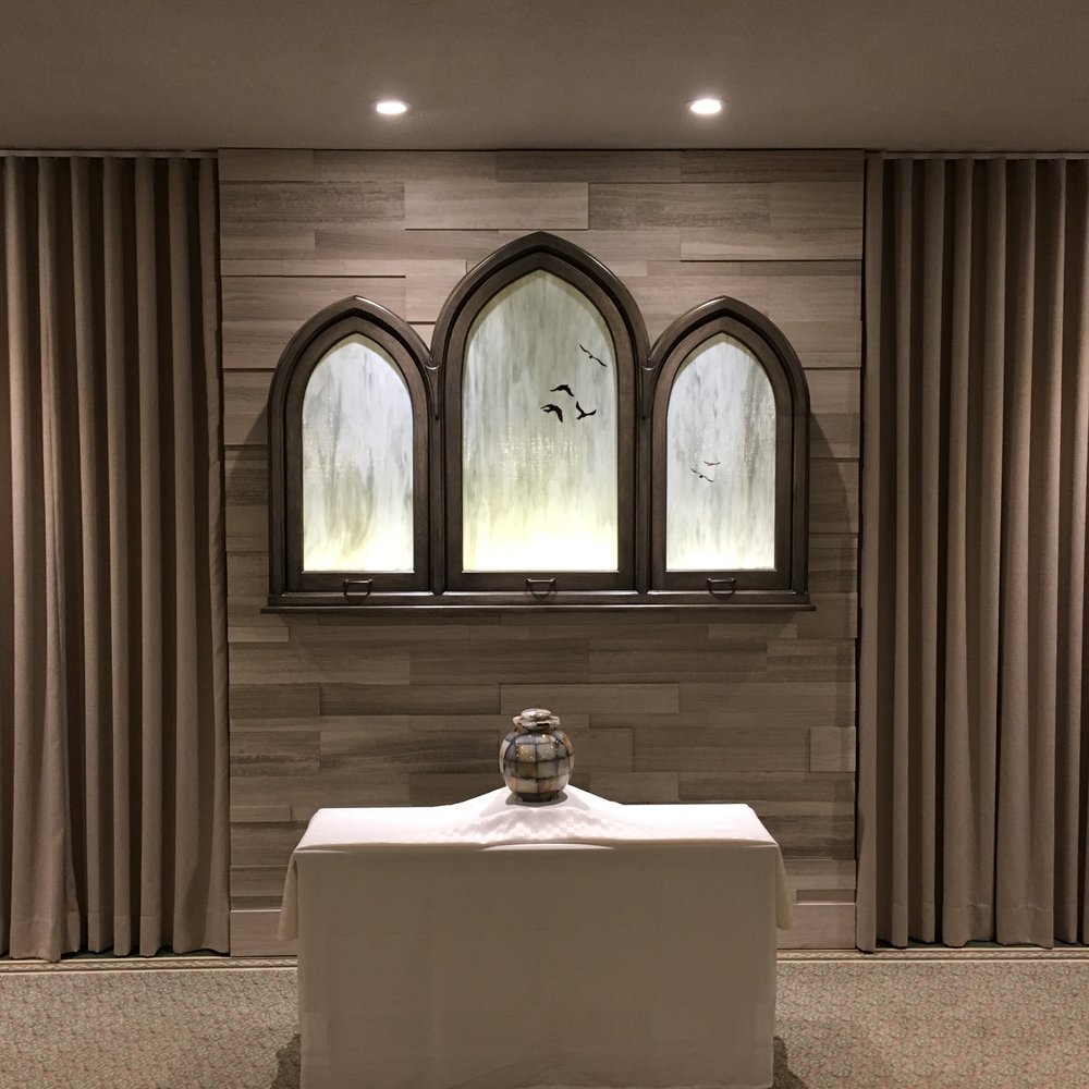 marble urn on a table at front of contemporary stained glass arches in chapel