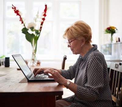older woman on laptop researching best price for funeral or cremation