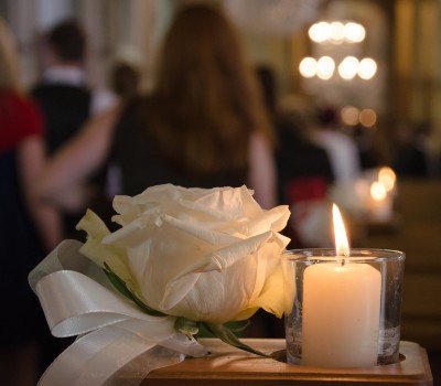 white rose and candle at a funeral or celebration of life